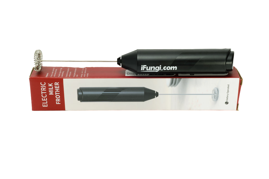 Black electric frother for mushroom powder supplement sitting on top of the packaging